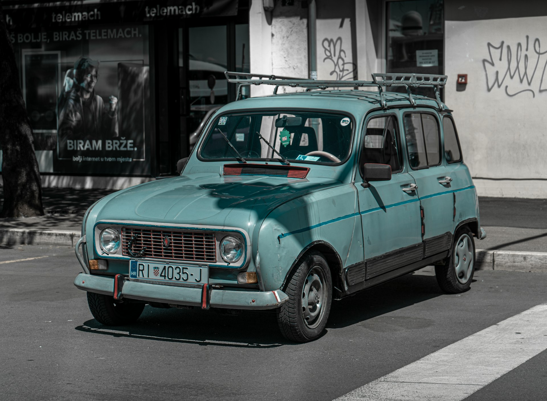 a small blue car parked on the side of the road